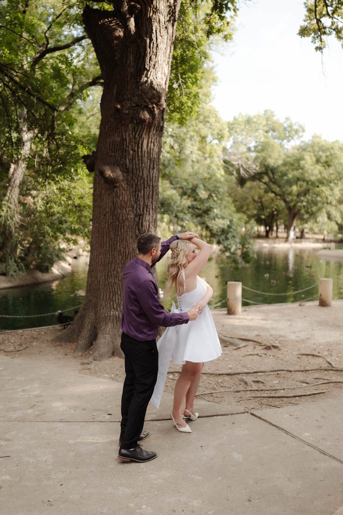 Bride and groom dancing and taking wedding portraits in front of the duck pond at Trinity Park in Fort Worth, TX