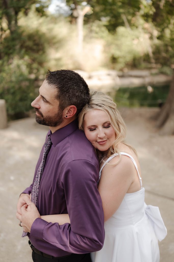 Bride and groom taking wedding portraits in front of the duck pond at Trinity Park in Fort Worth, TX