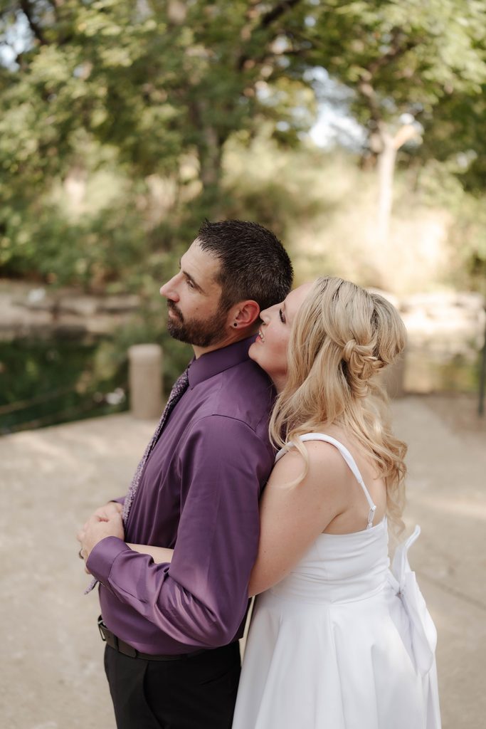 Bride and groom taking wedding portraits in front of the duck pond at Trinity Park in Fort Worth, TX
