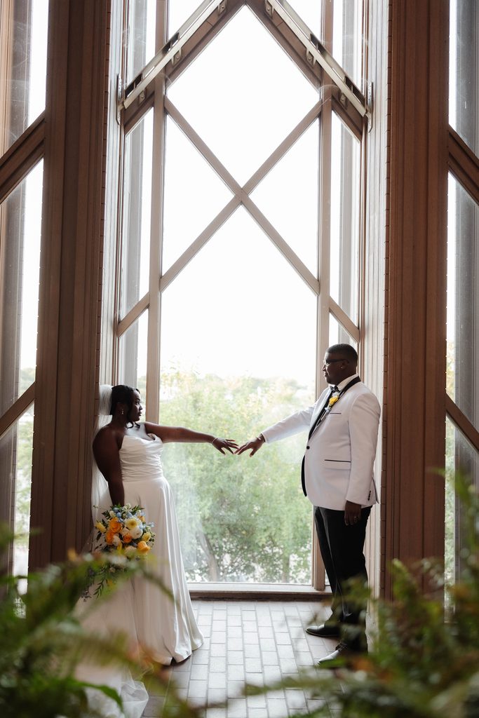 Bride and Groom posing in front of a window at Marty Leonard Chapel in Fort Worth, TX