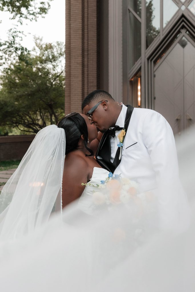 Bride and Groom kissing in front of Marty Leonard Chapel in Fort Worth, TX