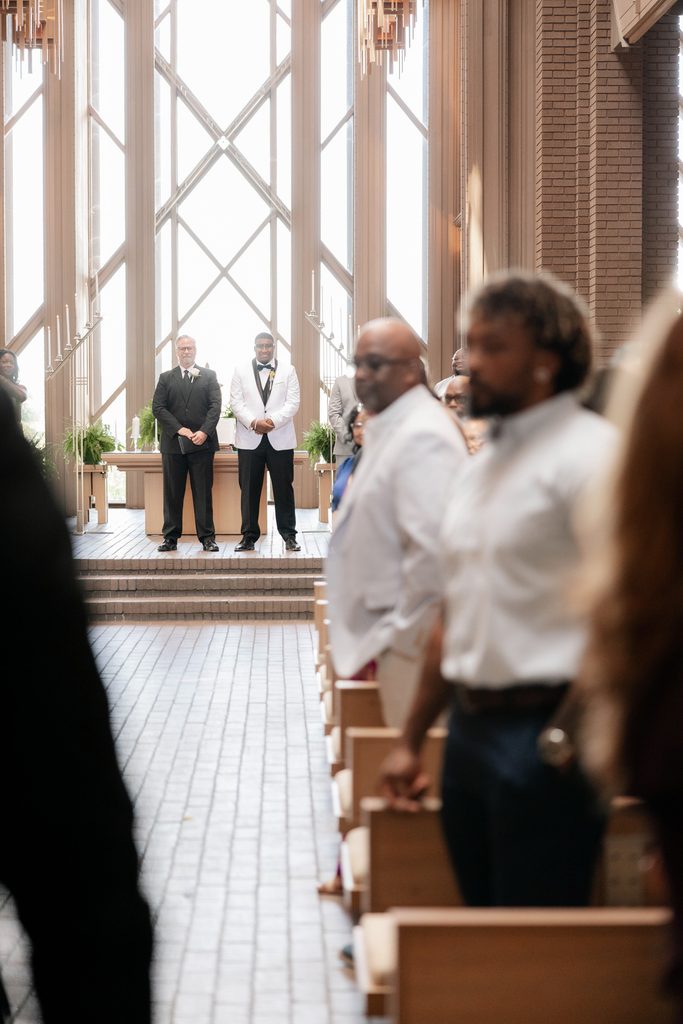 Groom happily awaiting his bride at the altar