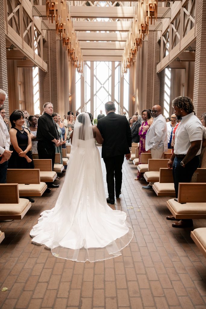 Bride and her father walk down the aisle towards the altar at the Marty Leonard Chapel