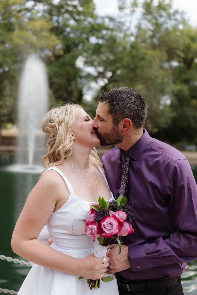 Bride and groom taking wedding portraits in front of the duck pond at Trinity Park in Fort Worth, TX