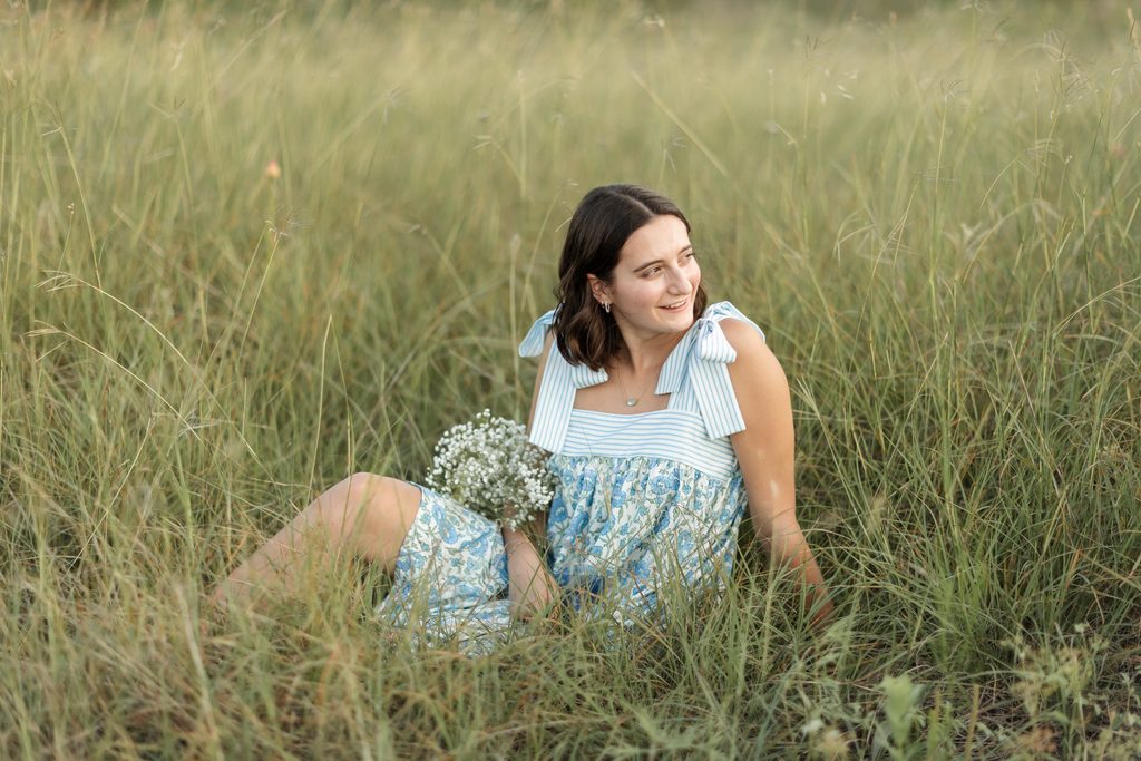 Girl sitting in an open field at Tandy Hills during her golden hour senior portrait session