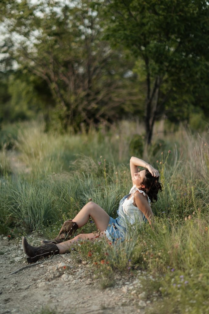 Girl sitting in an open field at Tandy Hills during her golden hour senior portrait session
