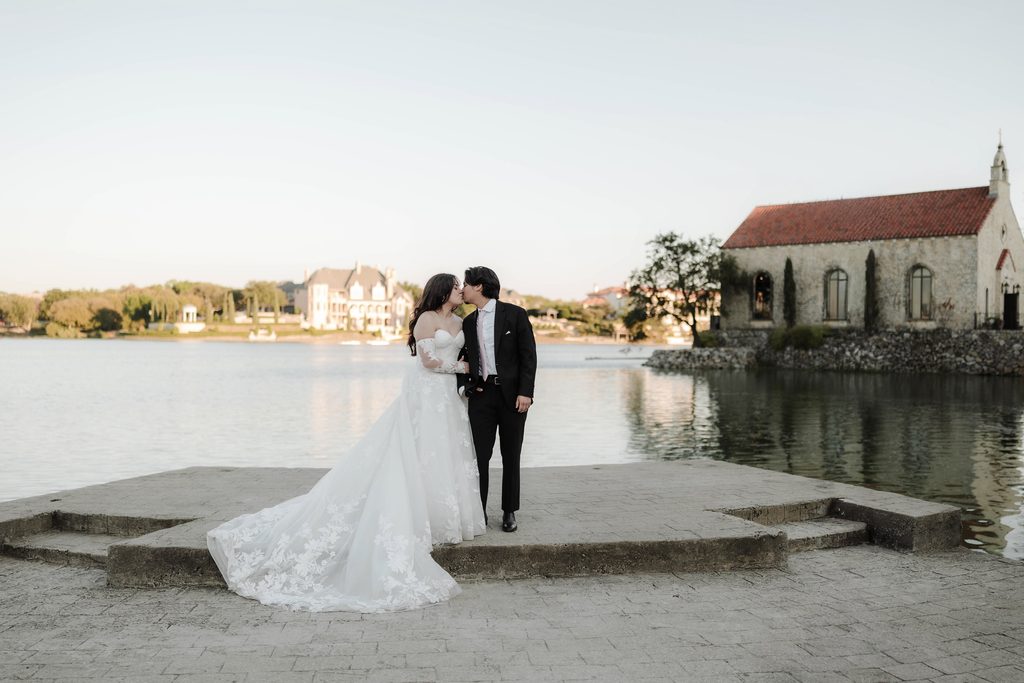 Bride and groom kissing with the chapel in the background at Adriatica Village