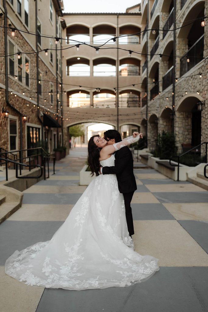 Bride and groom embracing in a kiss under the string lights at Adriatica Village