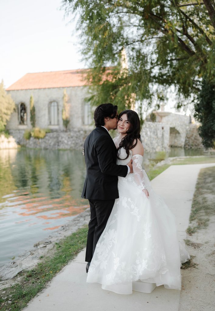 Bride and groom cuddling and walking along the water at Adriatica Village during their portrait session