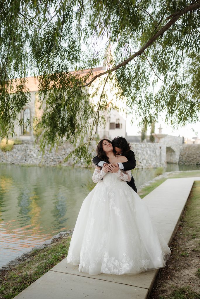 Bride and groom cuddling and walking along the water at Adriatica Village during their portrait session