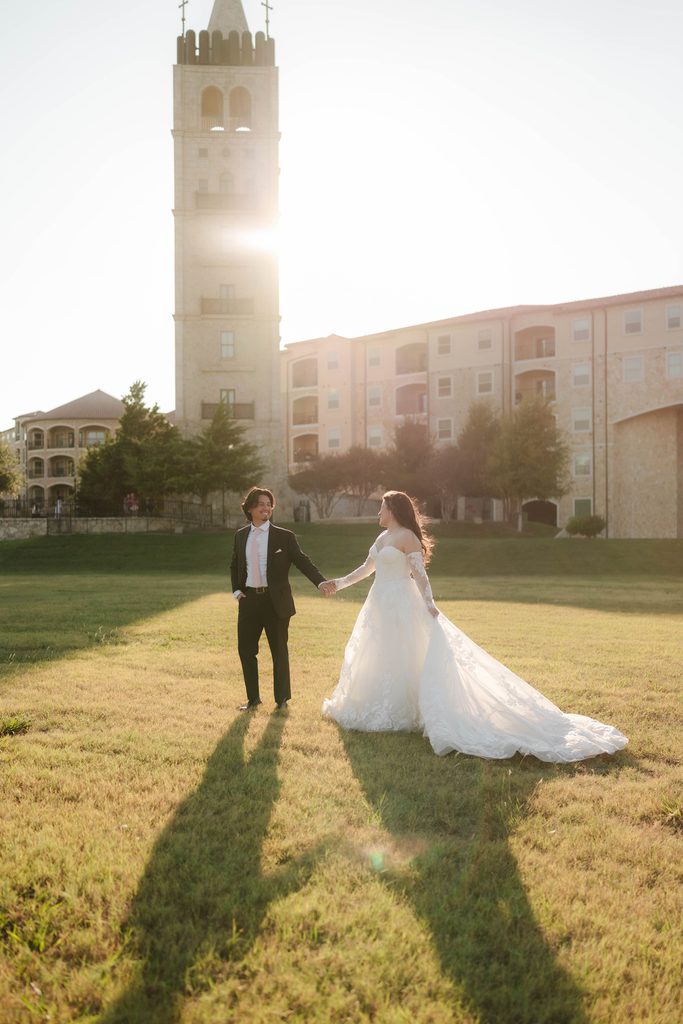 Bride and groom walking and holding hands while the sun sets behind them at Adriatica Village during their portrait session
