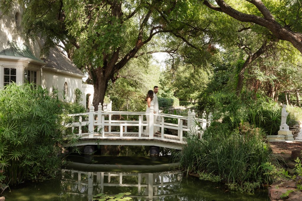 Man and woman walking across the koi pond bridge at Chandor Gardens in Weatherford, TX