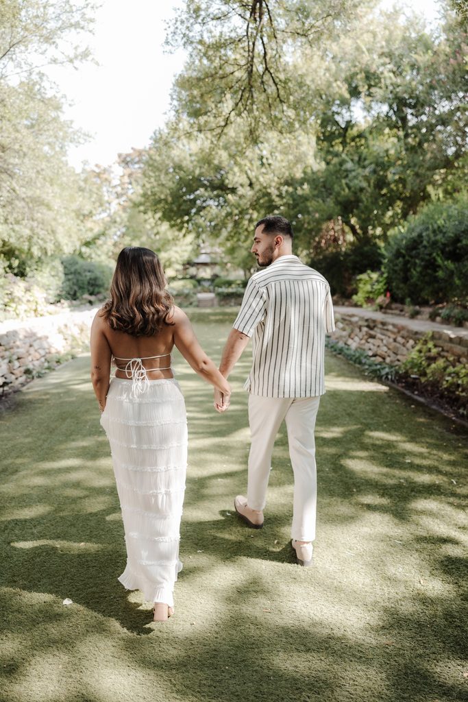 Fiancee's holding hands while frolicking down the green at Chandor Gardens, Weatherford, TX during a surprise proposal