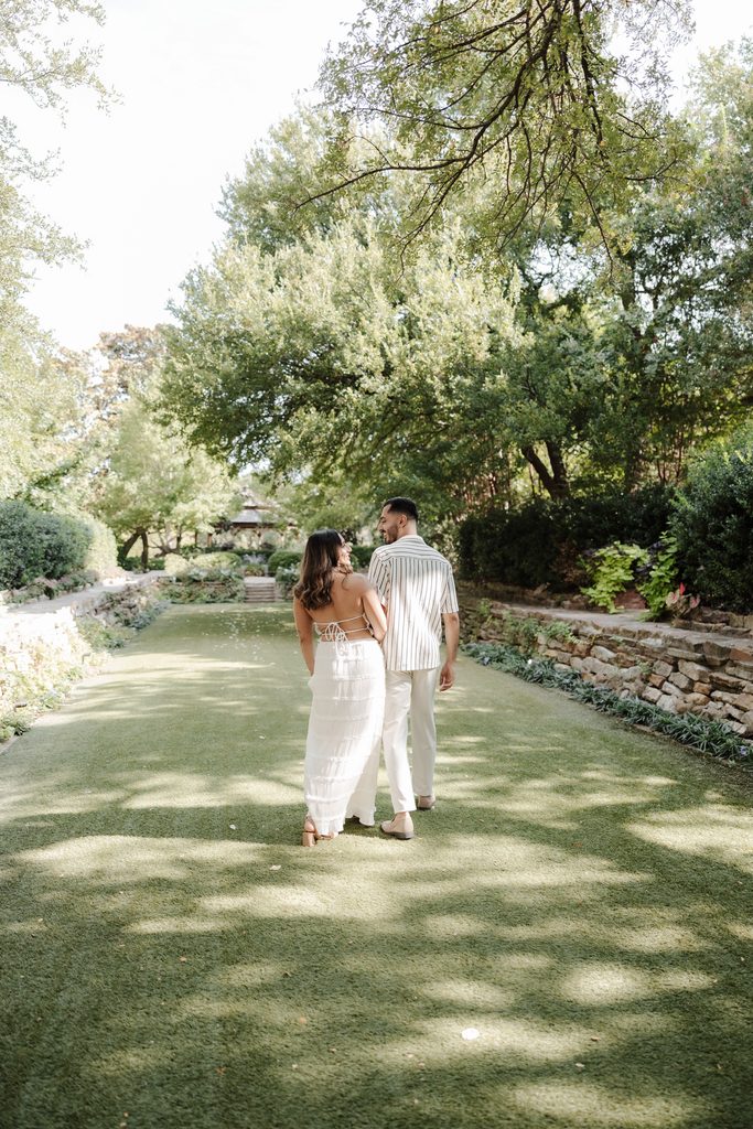 Fiancee's holding hands while frolicking down the green at Chandor Gardens, Weatherford, TX during a surprise proposal