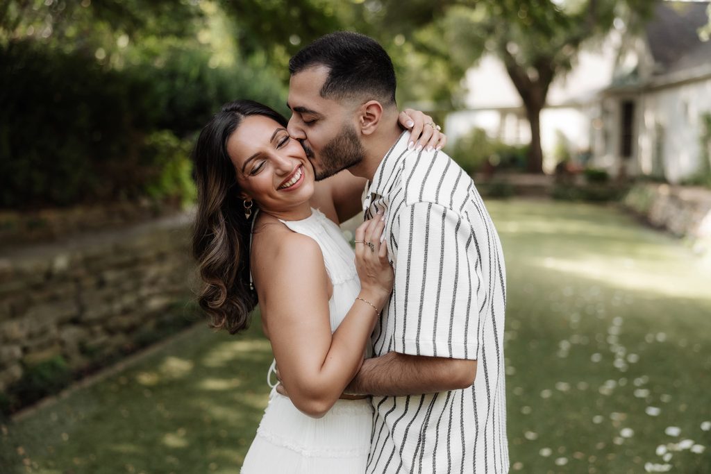 Man and woman kissing and cuddling at Chandor Gardens, Weatherford, TX during a surprise proposal
