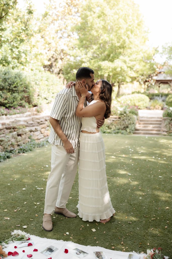 Man and woman kissing on the green at Chandor Gardens