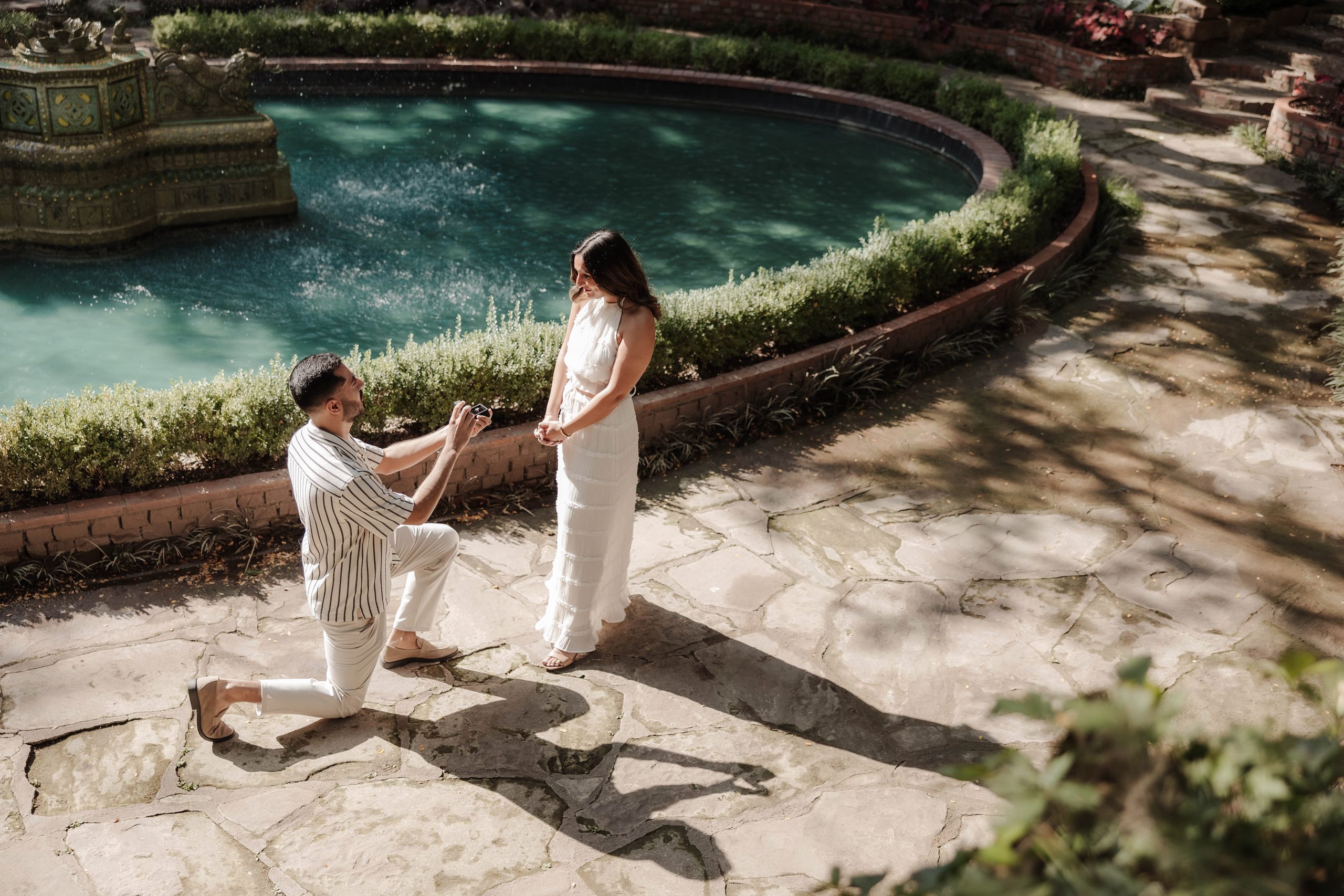 Man proposing to his girlfriend in front of the large water fountain at Chandor Gardens in Weatherford, TX