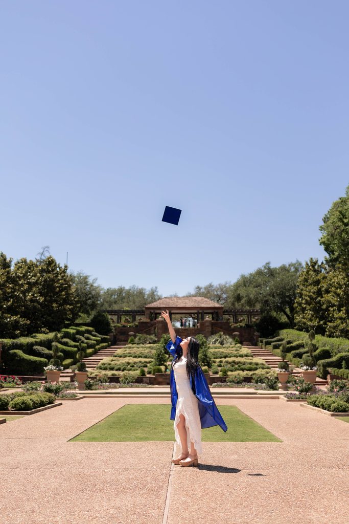 Portrait of girl throwing her grad cap in the air at the Fort Worth Botanic Garden during her senior portrait session