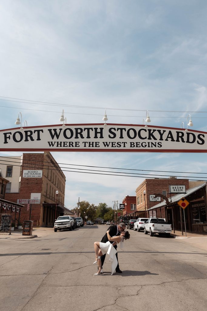 Bride and groom posing in front of the Fort Worth Stockyards Sign during their wedding