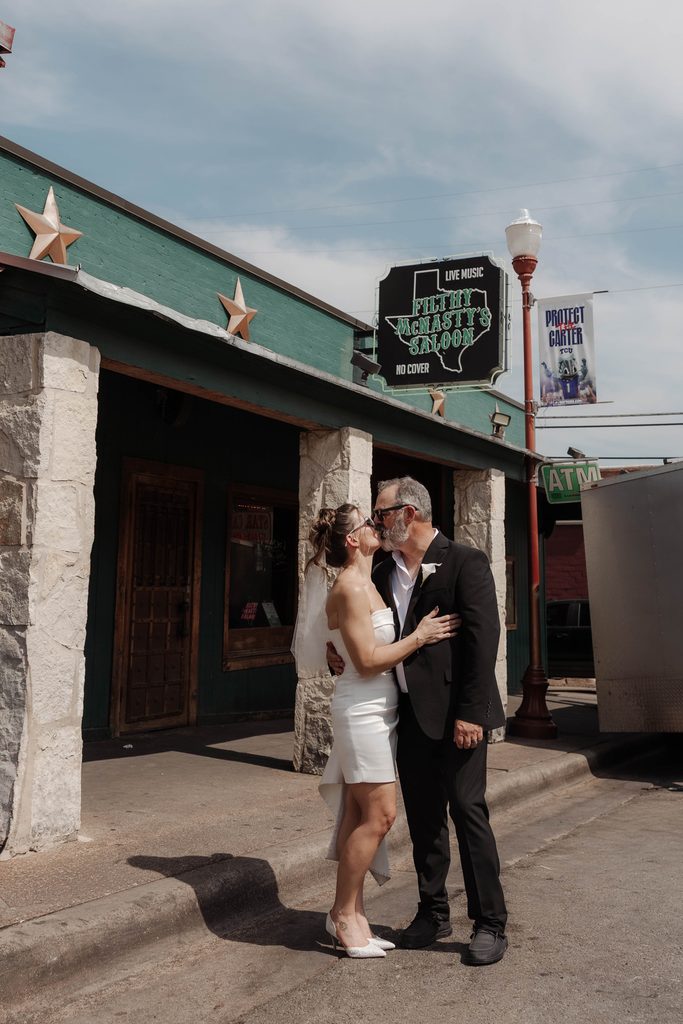 Bride and groom posing in front of Filthy McNasty's Bar during their wedding