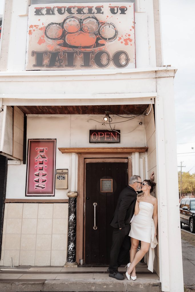 Bride and groom posing in front of Knuckle Up tattoo shop during their adventure elopement