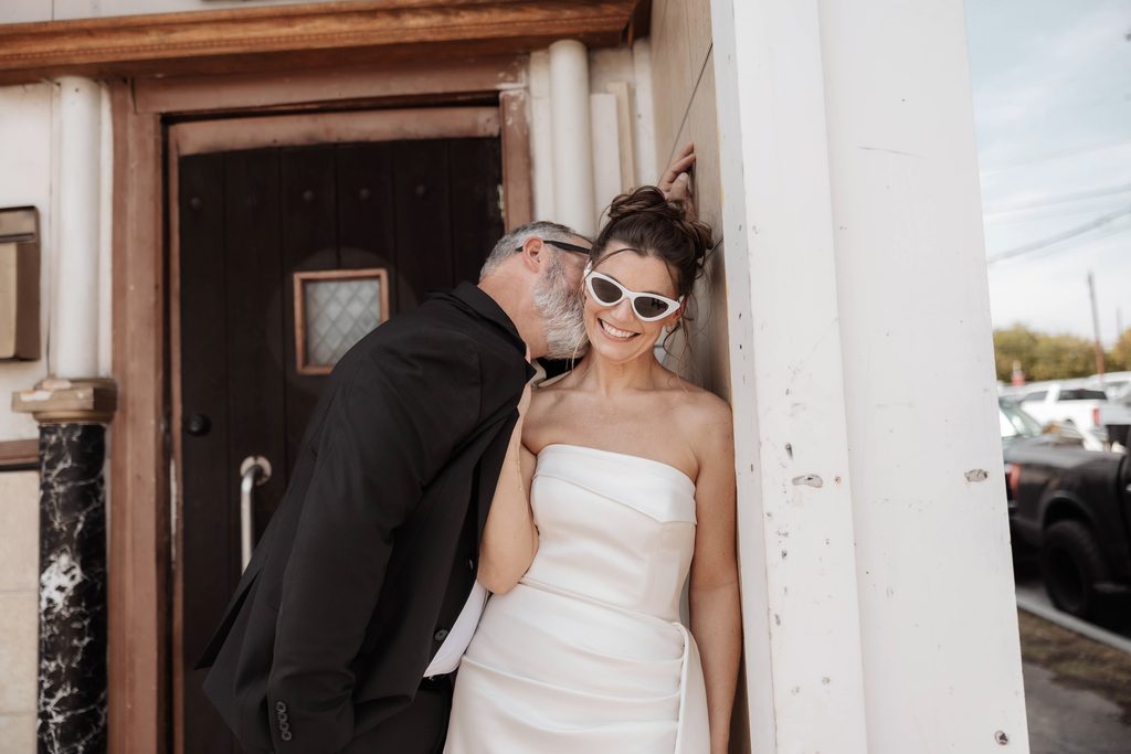 Bride and groom posing in front of Knuckle Up tattoo shop during their adventure elopement