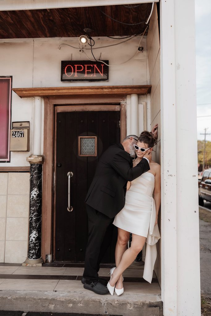 Bride and groom posing in front of Knuckle Up tattoo shop during their adventure elopement