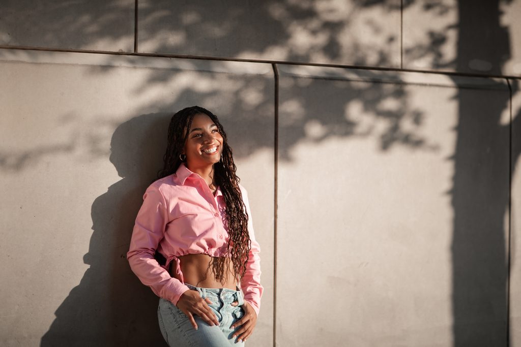 Dramatic lighting portrait of girl posing against a wall at the Fort Worth Water Gardens during her senior portrait session