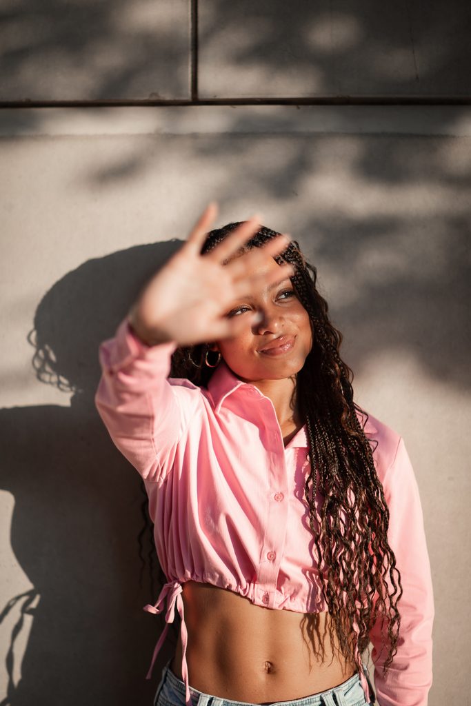 Dramatic lighting portrait of girl posing against a wall at the Fort Worth Water Gardens during her senior portrait session