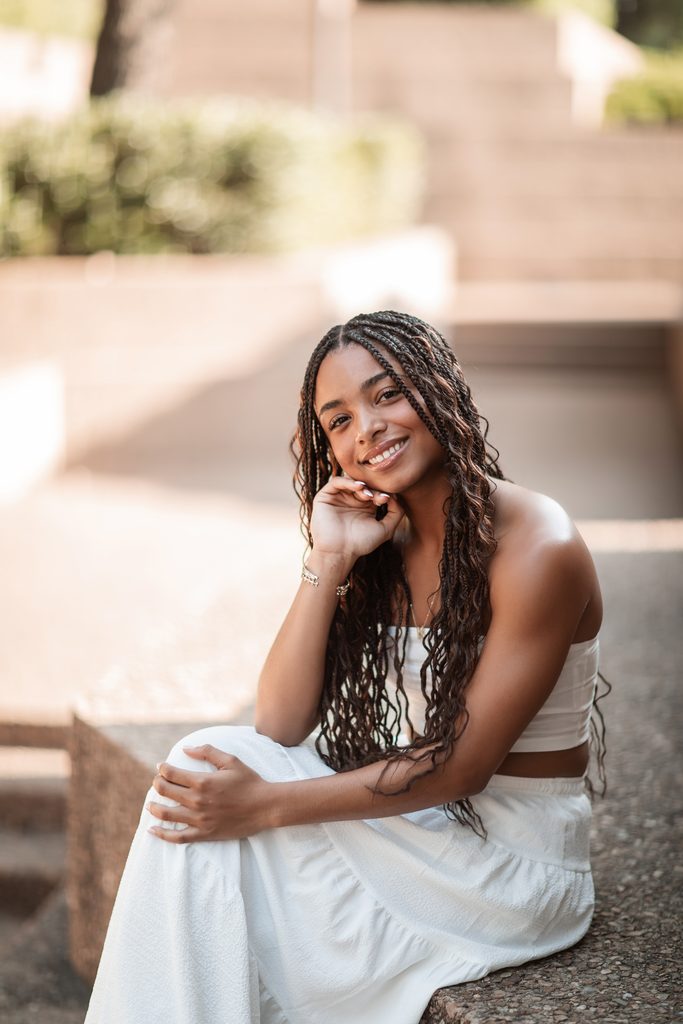 Dramatic lighting portrait of girl sitting at the Fort Worth Water Gardens during her senior portrait session