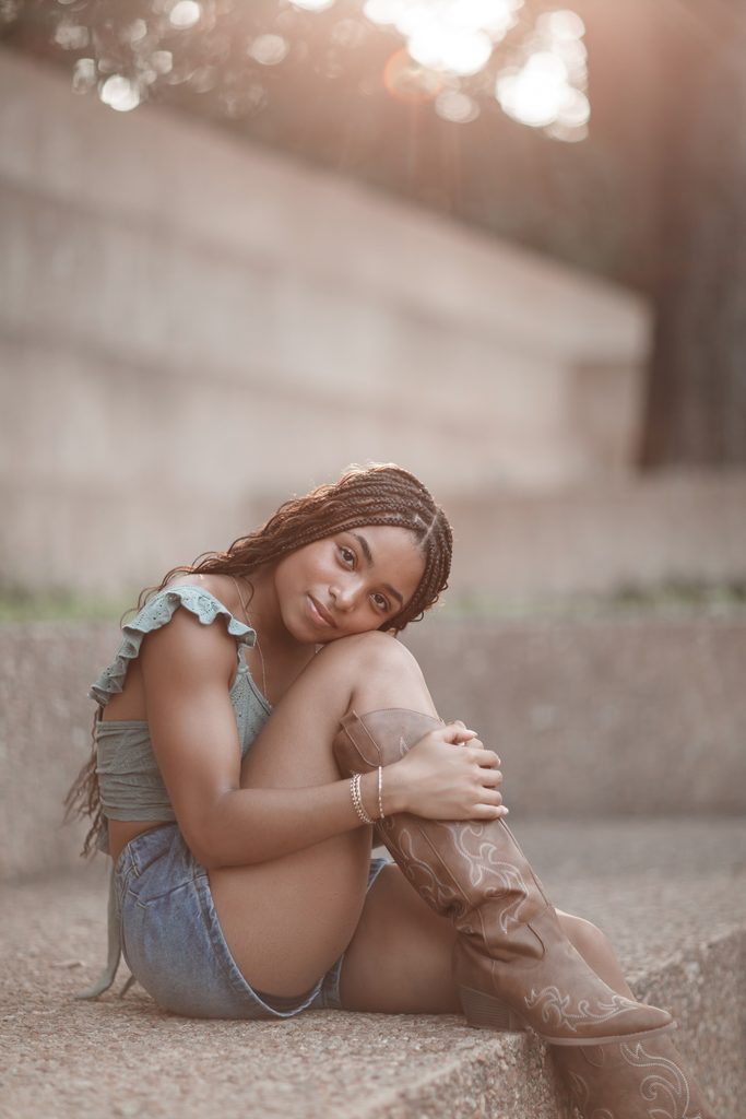 Dramatic lighting portrait of girl posing against a wall at the Fort Worth Water Gardens during her senior portrait session