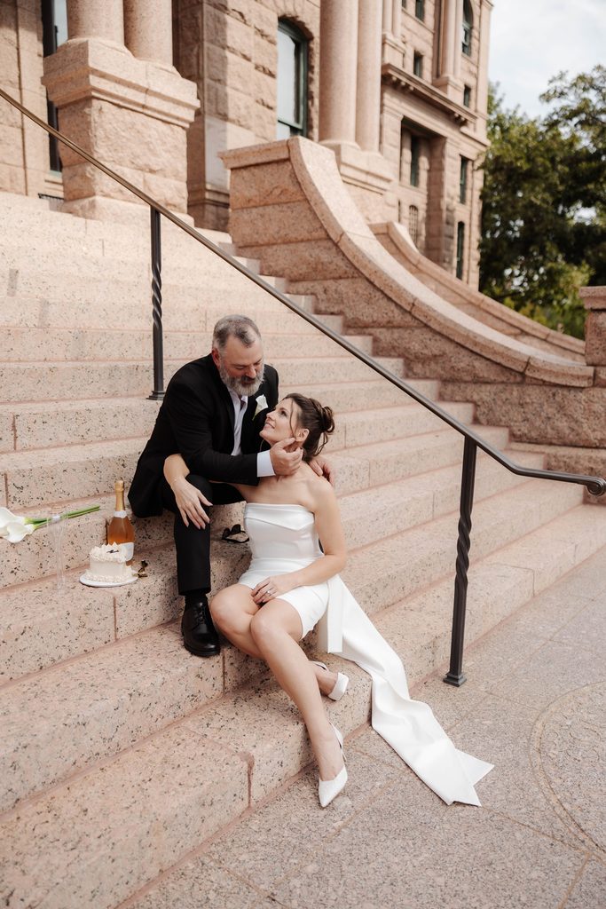 Bride + Groom sitting on the steps of the Fort Worth Courthouse 