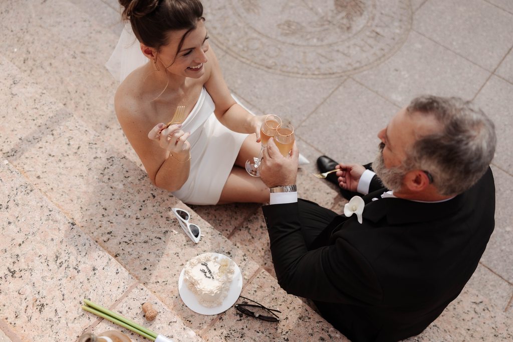 Bride + Groom eating cake on the steps of the Fort Worth Courthouse 