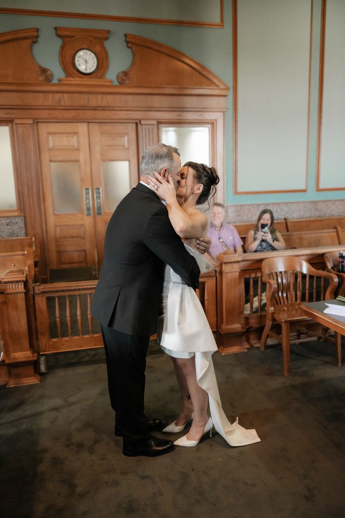 Bride + Groom kissing in the courtroom in the Tarrant County Courthouse during their adventure elopement in Fort Worth