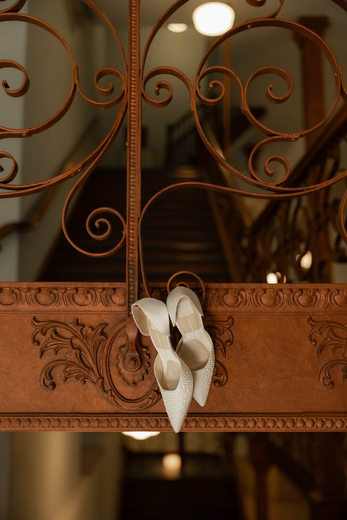 Detail shot of the bride's heels hanging from the staircase at the Tarrant County Courthouse