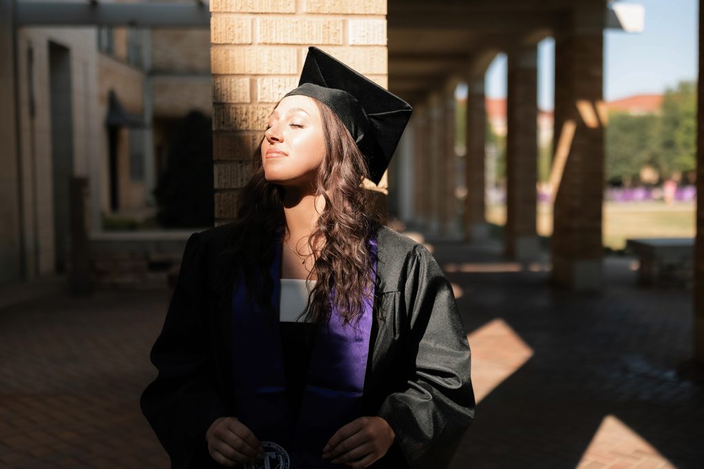 Dramatic lighting portrait of girl posing during her grad session at the TCU Campus in Fort Worth, TX